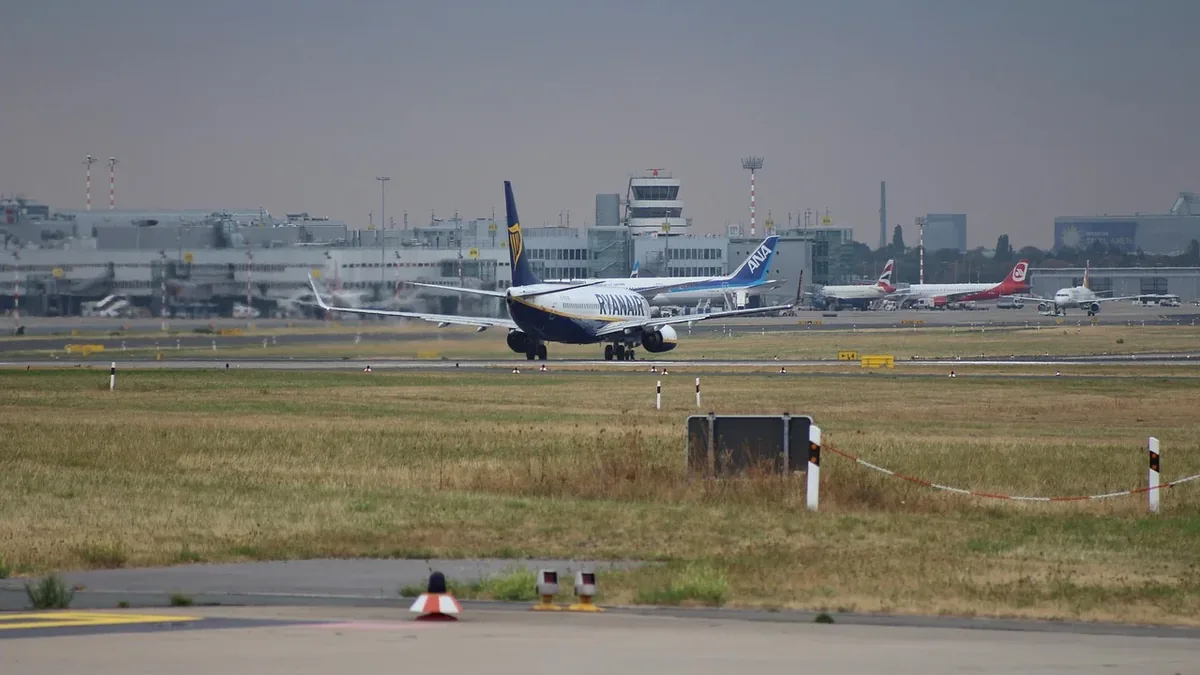 A commercial airplane on a runway, with other planes visible in the background.